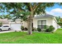 Charming single-Gathering home showcasing a well-manicured lawn, brick driveway, and attached two-car garage at 501 Lake Cummings Way, Lake Alfred, FL 33850