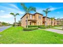 A charming view of a two-story townhome surrounded by lush green lawns and swaying palm trees at 109 Cambria Ave, Davenport, FL 33897