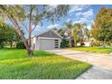 Beautifully landscaped front yard with mature trees framing the home, which features a two-car garage at 1315 Vista Del Lago Blvd, Dundee, FL 33838