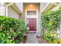 Inviting front entrance with a red door, surrounded by lush greenery and a hanging chair for relaxation at 1315 Vista Del Lago Blvd, Dundee, FL 33838