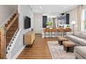 Stylish living room with wood floors, gray sofa, barstool seating at the kitchen counter, and wood-and-metal staircase at 140 Royal Ranch Rd, Clermont, FL 34715