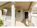 Covered front porch featuring a purple door, brick floor and beige walls at 14845 Speer Lake Dr, Winter Garden, FL 34787