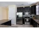 Modern kitchen boasting stainless steel appliances, dark cabinetry, granite countertops, and tile backsplash at 14845 Speer Lake Dr, Winter Garden, FL 34787