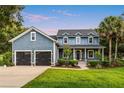 Charming two-story home with a well-manicured lawn, black garage doors, and inviting front porch at 16610 County Line Rd, Umatilla, FL 32784