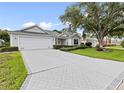 Well-maintained home with a brick driveway, manicured lawn, and mature landscaping at 16950 Se 80Th Bellavista Cir, The Villages, FL 32162