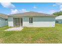 Home's back exterior showing a sliding door, lawn, and a small concrete patio at 2110 Mallard Creek Cir, Kissimmee, FL 34743