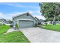 View of the home's side with a two-car garage, concrete driveway, and well-maintained landscaping at 2675 Bond St, Clermont, FL 34711