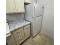 Well-equipped kitchen featuring white refrigerator, granite-style countertops and cabinet space at 415 Wymore Rd # 101, Altamonte Springs, FL 32714