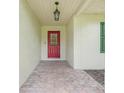 Covered front entry with brick flooring and a red front door at 6720 Midland Drive, St Cloud, FL 34771