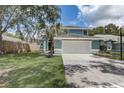 Two-story home featuring an attached two-car garage and mature trees in a manicured front yard at 10599 Satinwood Cir, Orlando, FL 32825