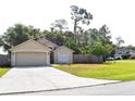 Charming one-story home with an attached garage, lush green lawn, and mature trees at 1436 Swan Ct, Kissimmee, FL 34759