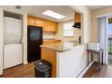 Compact kitchen featuring wood cabinets, black appliances, and a convenient washer/dryer setup at 2791 L B Mcleod Rd # C, Orlando, FL 32805