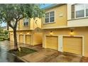 Charming yellow townhomes with individual garages, complimented by lush trees and colorful brick-lined driveway at 2820 Oakwater Dr # 2820, Kissimmee, FL 34747