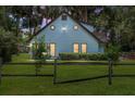 Lovely light blue home with unique round windows, a fenced yard, and ample outdoor lighting for charm and appeal at 3580 Ne 160Th Ln, Citra, FL 32113