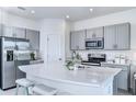 Bright, modern kitchen with stainless steel appliances, gray cabinets, and a large quartz island at 3603 Davenport Creek Ct, Kissimmee, FL 34746