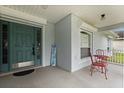 Inviting front porch with teal front door, window, and red chairs for relaxing outdoors at 3610 Doe Run Dr, St Cloud, FL 34772