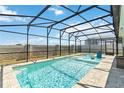 Inviting screened-in pool area featuring a refreshing swimming pool with relaxing in-pool seating and a modern privacy wall at 5627 Orange Orchard Dr, Winter Garden, FL 34787
