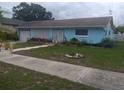 Quaint single-story home with a baby blue exterior, mature landscaping, and a white garage door at 833 Channing Rd, Lakeland, FL 33805