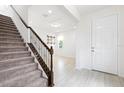 Inviting entryway featuring a carpeted staircase, wood railing, and light tile flooring leading to a bright living space at 12216 Encore At Ovation Way, Winter Garden, FL 34787