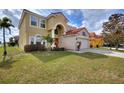 Charming two-story home featuring a red tile roof, arched entryway, manicured lawn, and a two-car garage at 148 Miro Dr, Davenport, FL 33837