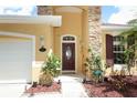 Close-up of the front entrance showcasing a decorative glass door, stone accents, and manicured landscaping at 203 Brookgreen Way, Deland, FL 32724