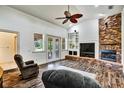 Open living room featuring vaulted ceilings, hardwood floors, brick fireplace, and French doors to the lanai at 205 Trail Bridge Ct, Winter Garden, FL 34787