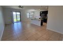Spacious living room with tile floors, black kitchen cabinets, and a view of the pond at 2355 Seven Oaks Dr, St Cloud, FL 34772