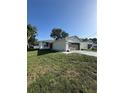 Single-story home with a neutral exterior paint job, fresh green grass and a long driveway at 320 W Necho Ave, Lake Alfred, FL 33850