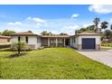 Charming single-story home with stone accents, a well-manicured lawn, and a blue garage door at 338 Henry Butts Dr, Daytona Beach, FL 32114