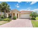 Inviting single-story home with tile roof, brick driveway, manicured lawn, and lush tropical landscaping at 3906 Carrick Bend Dr, Kissimmee, FL 34746