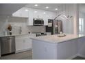 Modern kitchen features stainless steel appliances, white cabinetry, and an island with quartz countertops at 438 Romano Ave, Orlando, FL 32807
