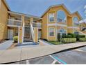 Exterior view of a sunny yellow condominium building with two stories and covered walkways to the entrance at 8709 Knightsbridge Ct # B, Kissimmee, FL 34747
