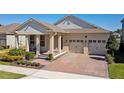 Charming home exterior featuring a brick driveway, a front porch, and a two-car garage at 8935 Sonoma Coast Dr, Winter Garden, FL 34787