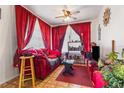 Cozy living room with bright red curtains, ceiling fan and ample natural light at 105 N Florida Ave, Howey In The Hills, FL 34737