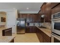 Kitchen featuring stainless steel appliances, granite countertops, dark wood cabinets, and tile backsplash at 1156 Castle Pines Ct, Reunion, FL 34747