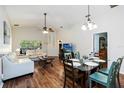 Open-concept living room with wood floors and adjacent dining area offers comfortable living at 165 Scrub Jay Way, Davenport, FL 33896