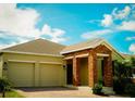 The home's facade features a two-car garage and a welcoming brick-columned entryway at 1889 Blissful Dr, Kissimmee, FL 34744