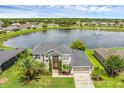 Stunning aerial view of a gray two-story home near a serene lake and fountain at 3131 Regal Darner Dr, Kissimmee, FL 34744