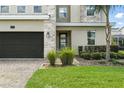 Close up of a charming two-story home featuring stone accents, a two-car garage, and a well-manicured lawn at 369 Ocean Course Ave, Davenport, FL 33896