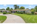 Landscaped front yard with healthy green grass and a winding driveway leading to a well-maintained single-story home at 3722 Neptune Dr, Orlando, FL 32804