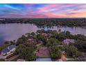 Breathtaking aerial view of a home on the water with surrounding trees at sunset at 446 Alberta Dr, Winter Park, FL 32789