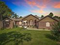 Charming single-story home featuring brick accents, manicured lawn, and inviting curb appeal under a sunset at 448 Warrior Trl, Deltona, FL 32725