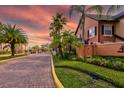 A beautifully landscaped entrance to a gated community with palm trees and a colorful sunset at 6029 Westgate Dr # 726, Orlando, FL 32835