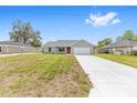 A single-story home with a bright red front door, freshly painted exterior, and a concrete driveway at 654 Ne 130Th Ct, Silver Springs, FL 34488