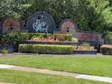 Community entrance sign with manicured hedges and flower beds at 8012 Old Town Dr, Orlando, FL 32819