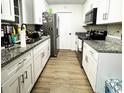 Galley kitchen features granite counters, wood floor, and white cabinets at 1211 Phillip St, Winter Springs, FL 32708