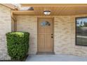 Close-up of a tan front door with decorative window, surrounded by brick and trimmed bushes at 1299 Buccaneer Ave, Deltona, FL 32725