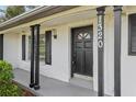 Close-up of the home's entrance highlights the black door, decorative columns, and updated lighting fixture at 1320 E Lombardy Dr, Deltona, FL 32725