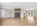 Open-concept living room with a brick fireplace and hardwood flooring flowing into the kitchen at 28 N Osceola Ave, Center Hill, FL 33514
