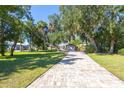 Paver driveway leading to a charming single-story home with lush landscaping and beautiful curb appeal at 418 Acacia Cir, Port Orange, FL 32127